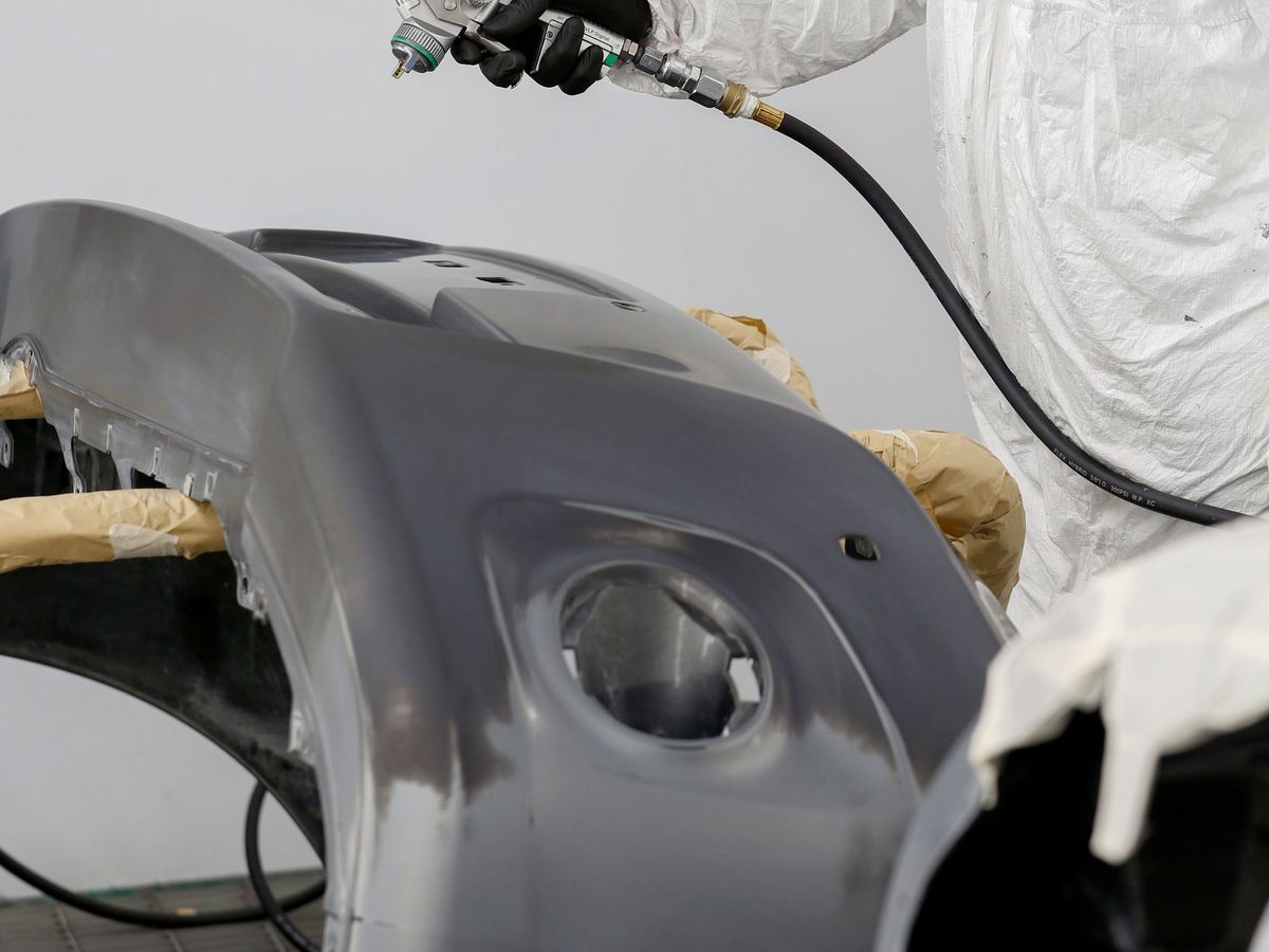 Car bumper being spray painted in a panel shop